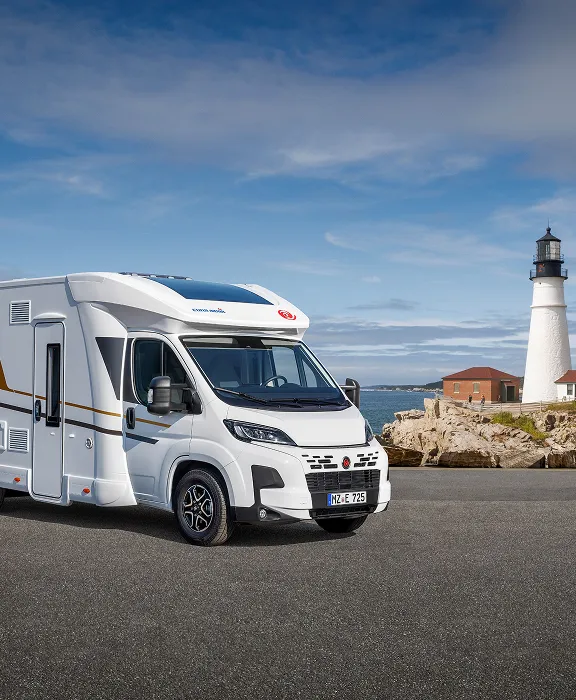Paar genießt ein gemeinsames Frühstück mit Sekt im gemütlichen Innenraum eines modernen Wohnmobils mit Küchenzeile und großer Fensterfront.